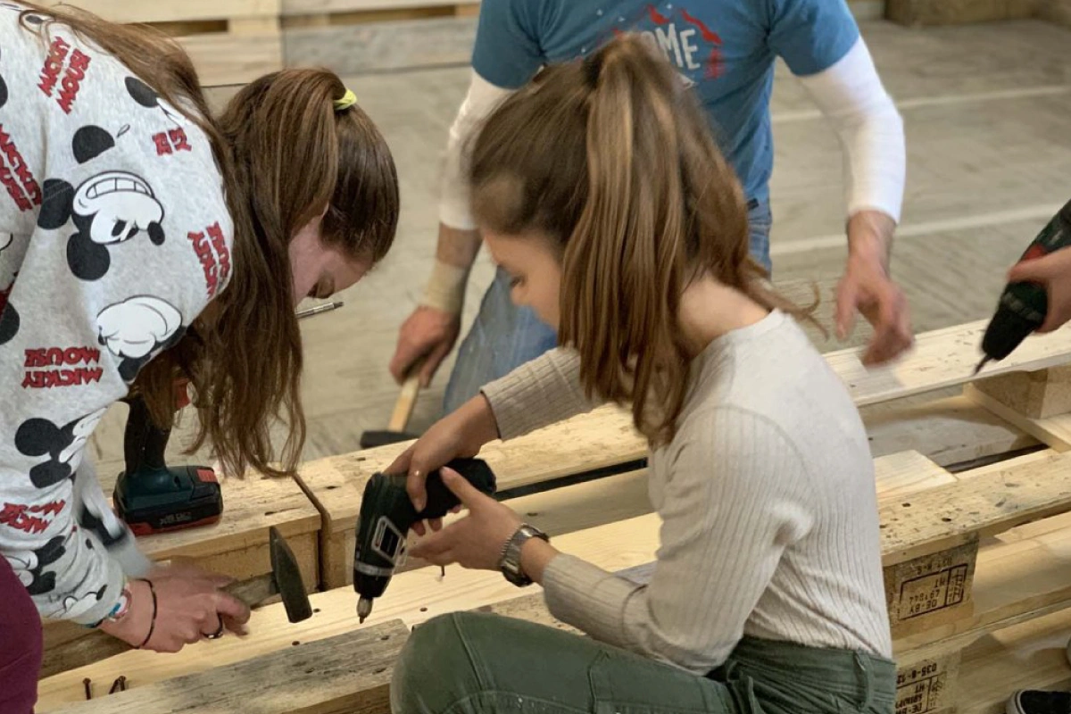 Immagine dell’articolo “Una scuola sostenibile negli arredi”. Raffigura dei bambini mentre costruiscono arredi con il pallet.