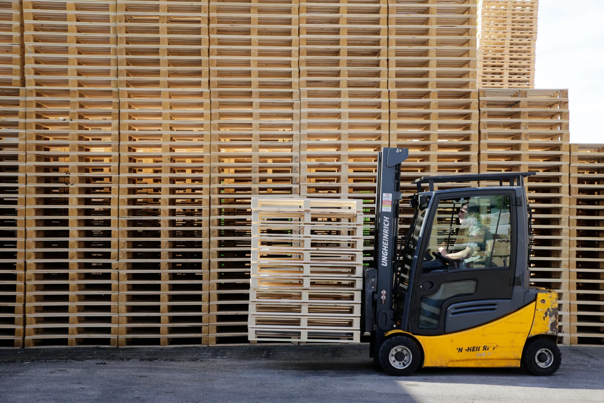 Immagine dell’articolo “ I vantaggi dell’utilizzo dei pallet nella logistica”. Raffigura un muletto che trasporta del pallet.